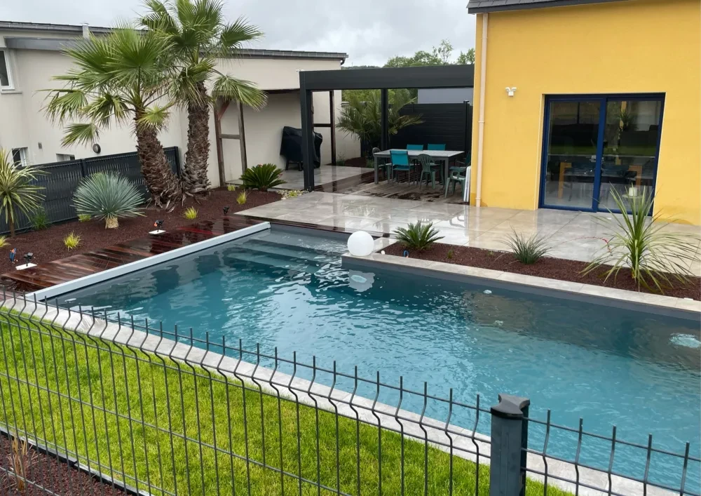 Piscine rectangulaire extérieure avec liner bleu-gris, entourée d'une plage en carrelage travertin beige et d'une terrasse en bois ipé