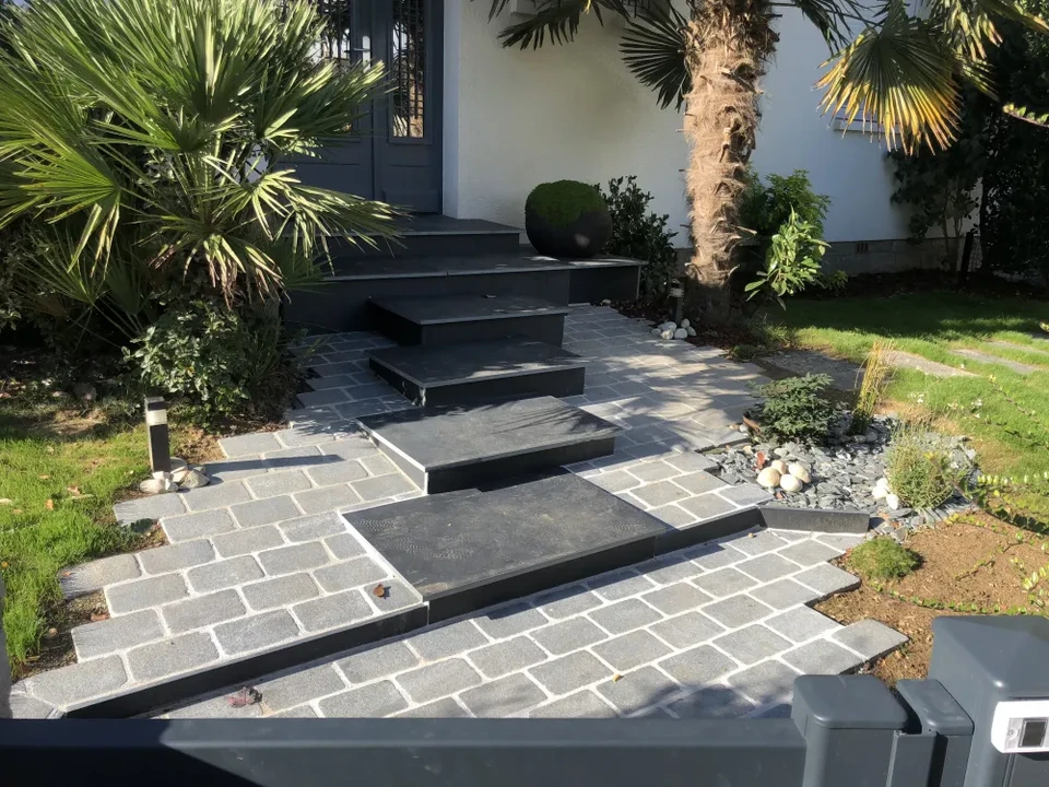 Entrée de maison moderne avec escalier en granit noir flammé, trois marches larges en porte-à-faux