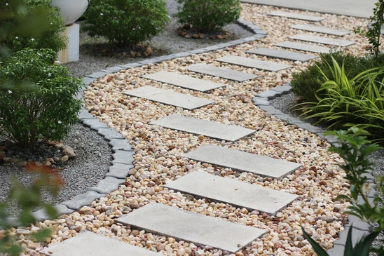 Jardin paysager extérieur avec allée de pas japonais circulaires en béton coulé, disposés de manière organique sur paillis d'écorce sombre