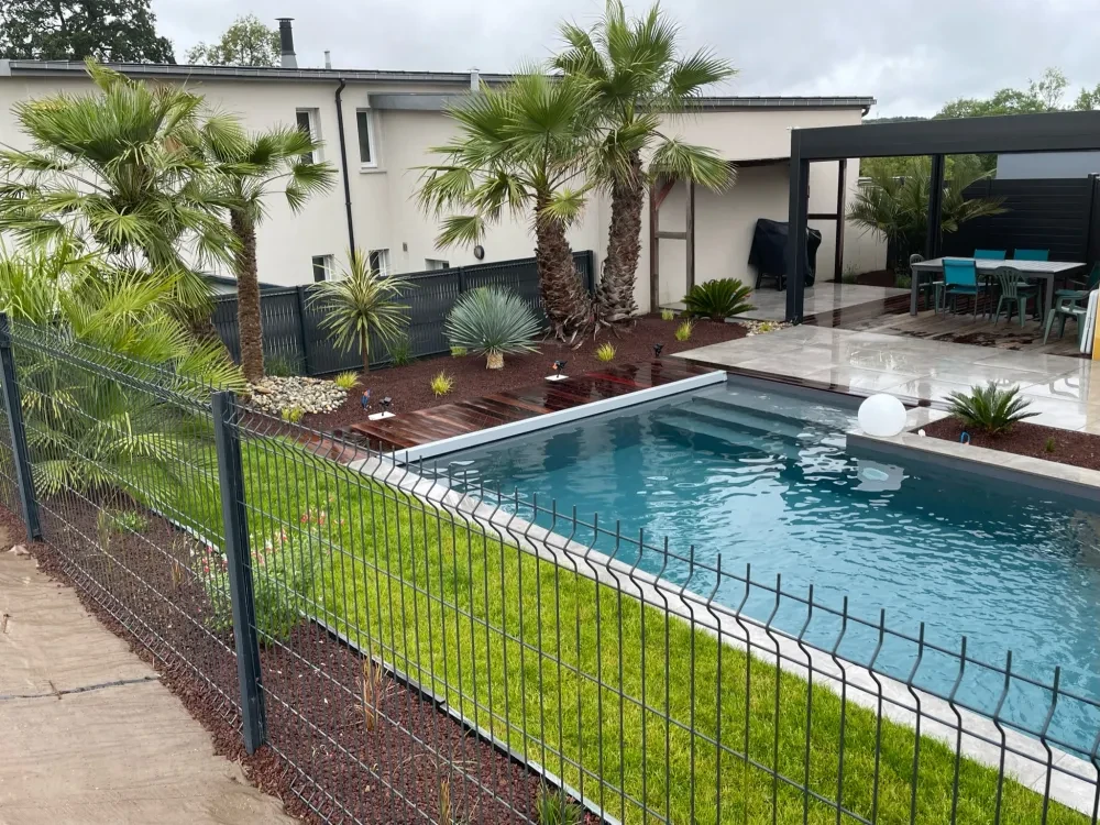 Aménagement paysager extérieur de style contemporain : massif avec paillage de copeaux roux, gravier blanc calcaire, arbuste à port naturel type pittosporum, palmier Trachycarpus