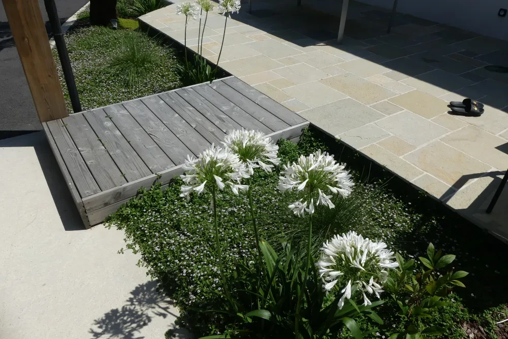 Terrasse couverte moderne avec pergola bioclimatique à lames orientables en aluminium anthracite, adossée à une maison contemporaine
